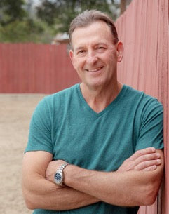 Dr. Edwin “Ted” Simpson, founder of LITMUS, smiling with his arms crossed outdoors.