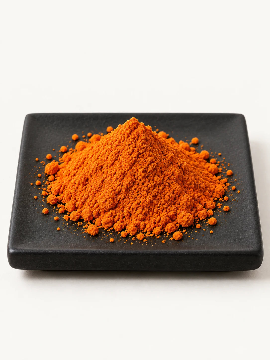 Illustrative orange beta-carotene material on a black plate.