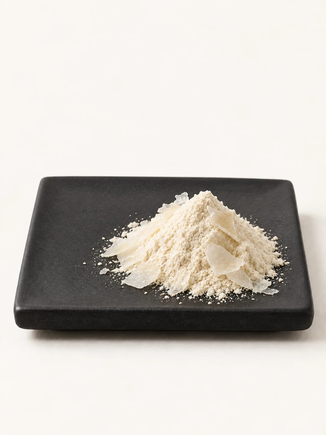 Illustrative pale CM chitosan powder and flakes on a black plate.