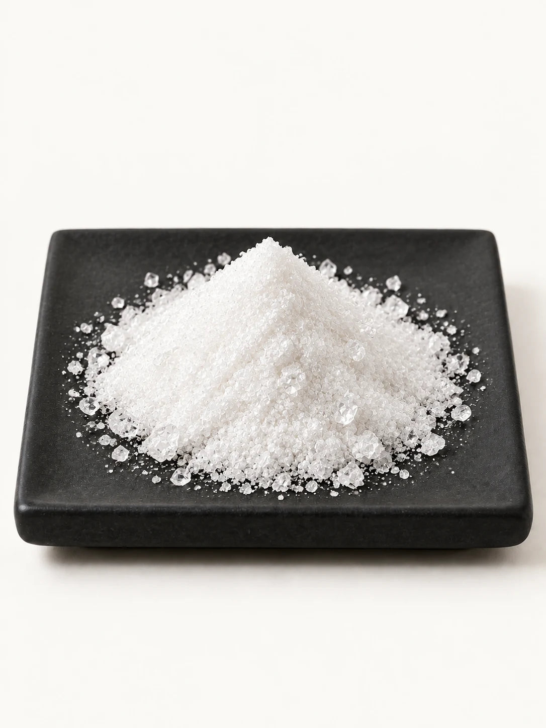 Illustrative white vitamin C crystals on a black plate.